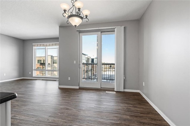 unfurnished dining area featuring a textured ceiling, dark wood-style flooring, and baseboards