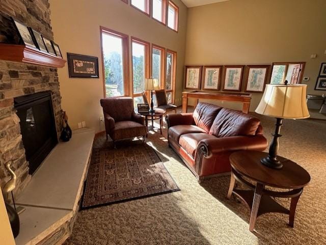 carpeted living room featuring a high ceiling and a stone fireplace