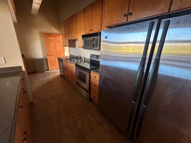 kitchen with appliances with stainless steel finishes, a sink, and dark countertops
