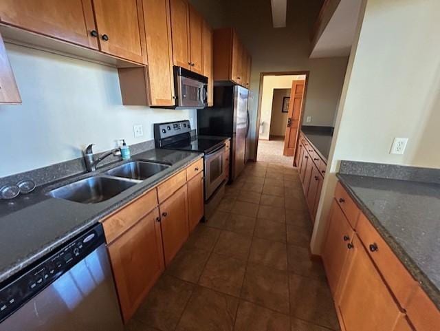 kitchen featuring a sink, brown cabinetry, appliances with stainless steel finishes, and dark tile patterned floors