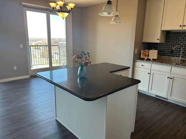 kitchen featuring a sink, dark countertops, a notable chandelier, and dark wood finished floors