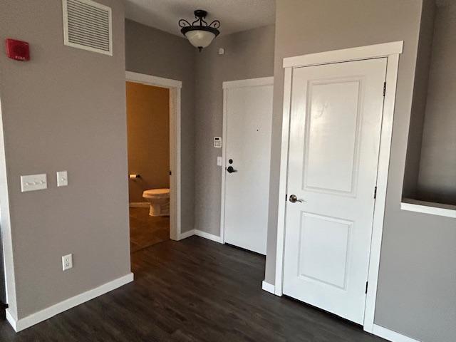 interior space featuring baseboards, dark wood-style floors, and visible vents