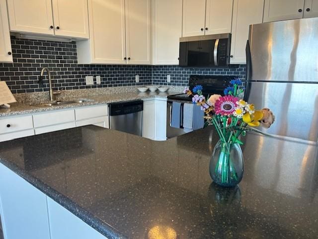 kitchen featuring appliances with stainless steel finishes, decorative backsplash, a sink, and white cabinets