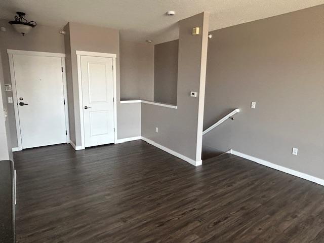 empty room featuring dark wood-style flooring and baseboards