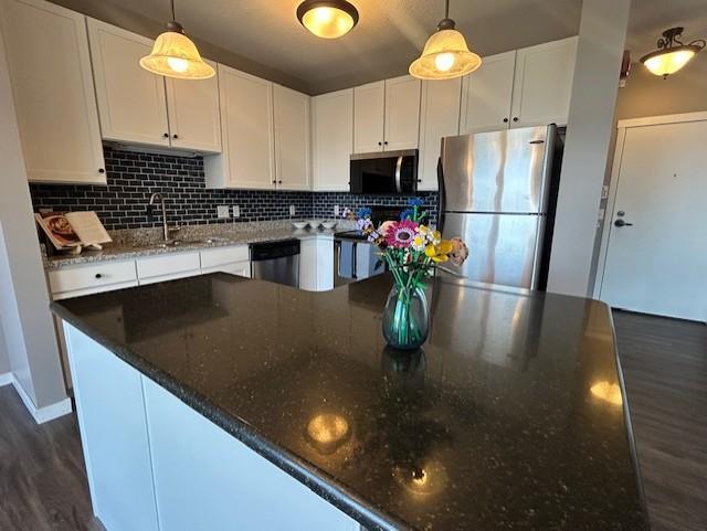 kitchen with dark wood finished floors, white cabinetry, and appliances with stainless steel finishes