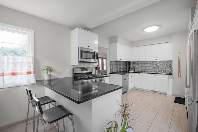 2136 Temple Ct, Saint Paul, MN 55104 - kitchen with appliances with stainless steel finishes, a peninsula, healthy amount of natural light, and backsplash