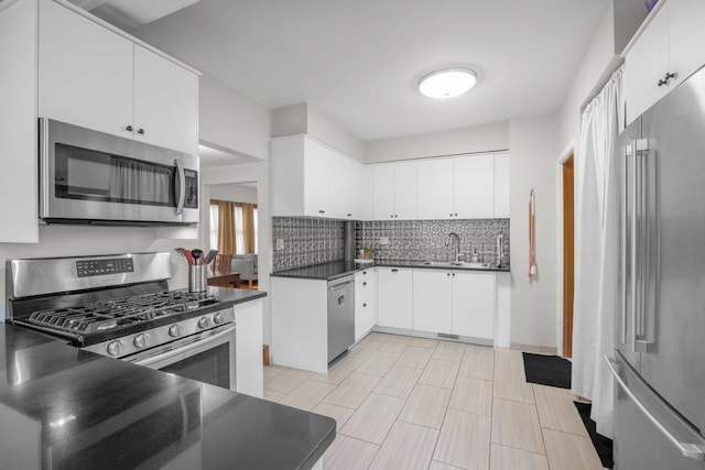 2136 Temple Ct, Saint Paul, MN 55104 - kitchen with stainless steel appliances, dark countertops, backsplash, a sink, and white cabinets