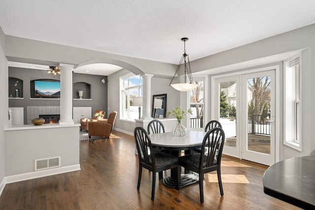 dining area with ornate columns, visible vents, a glass covered fireplace, and a healthy amount of sunlight