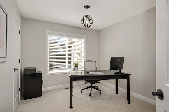 office area with a textured ceiling, baseboards, and light colored carpet