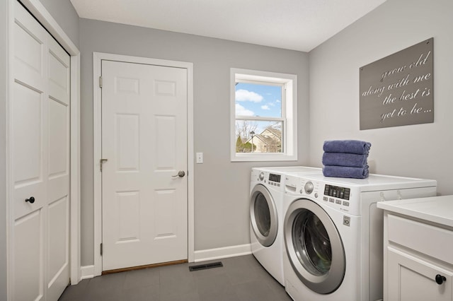 clothes washing area with dark tile patterned floors, laundry area, visible vents, baseboards, and separate washer and dryer