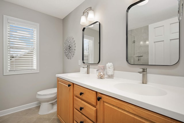 bathroom featuring a sink, baseboards, a tile shower, and a healthy amount of sunlight