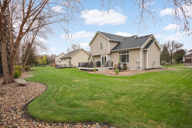 rear view of house featuring a yard, a deck, a shingled roof, and a patio area