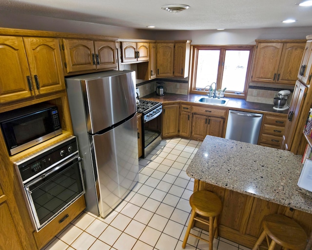 32990 Heilberger Dr, Erhard, MN 56534 - kitchen with appliances with stainless steel finishes, a sink, light tile patterned floors, brown cabinetry, and a kitchen bar