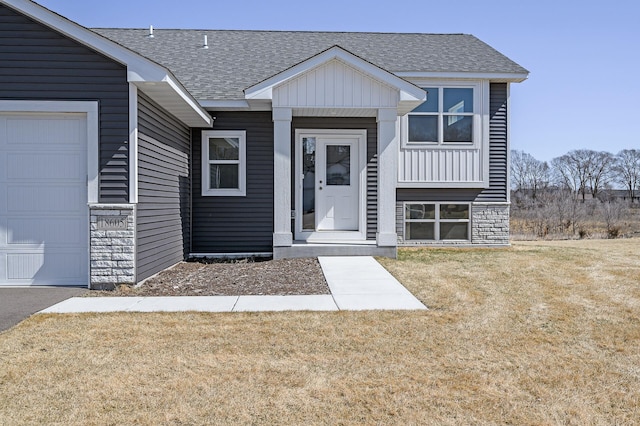 view of front of house with a garage, a front lawn, stone siding, and a shingled roof