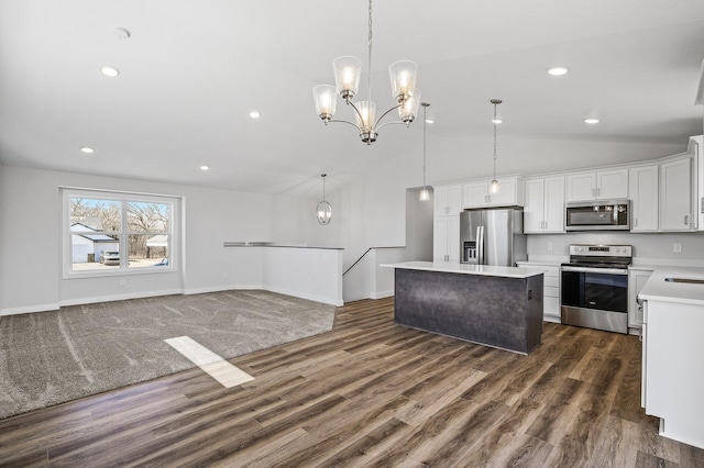 kitchen featuring an inviting chandelier, vaulted ceiling, a kitchen island, appliances with stainless steel finishes, and light countertops