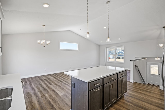 kitchen featuring a center island, an inviting chandelier, light countertops, vaulted ceiling, and dark wood-type flooring