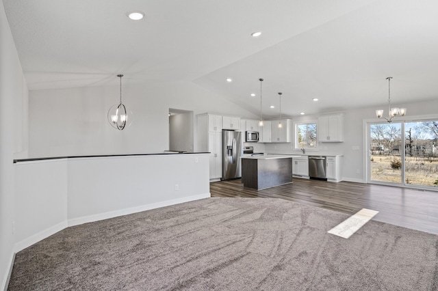 kitchen featuring white cabinetry, a center island, appliances with stainless steel finishes, open floor plan, and a notable chandelier