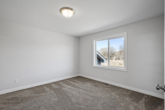 unfurnished room with visible vents, baseboards, dark colored carpet, and a textured ceiling