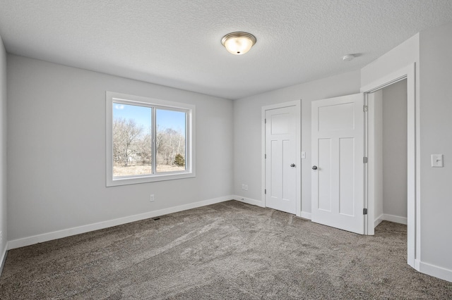 unfurnished bedroom featuring a textured ceiling, a closet, baseboards, and carpet floors