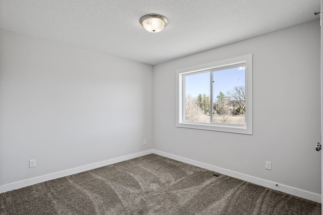 carpeted spare room with a textured ceiling and baseboards