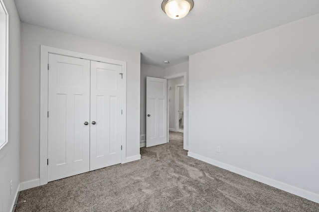 unfurnished bedroom featuring a closet, carpet flooring, baseboards, and a textured ceiling