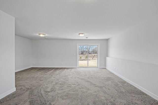 spare room with carpet, baseboards, and a textured ceiling