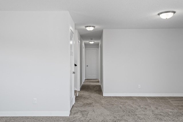 hall with carpet, baseboards, and a textured ceiling