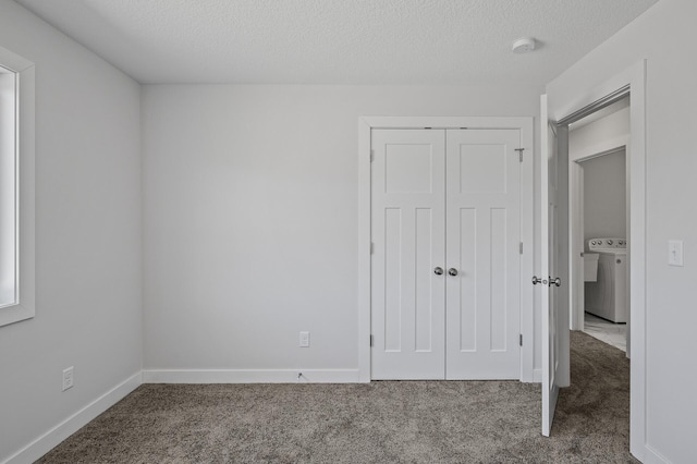unfurnished bedroom featuring washer / clothes dryer, a closet, carpet floors, and a textured ceiling