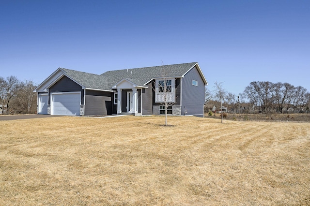 view of front of home with an attached garage, a shingled roof, and a front lawn