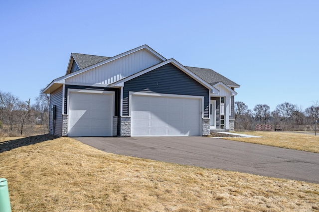 exterior space with an attached garage, stone siding, driveway, and a front lawn