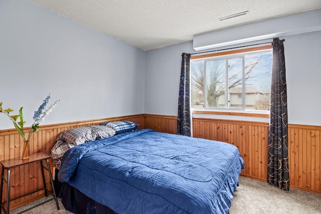 103 8th St N, Sartell, MN 56377 - bedroom with a textured ceiling, wainscoting, wooden walls, carpet floors, and visible vents