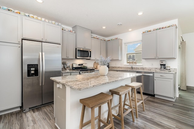 kitchen with a sink, gray cabinets, a center island, appliances with stainless steel finishes, and wood finished floors