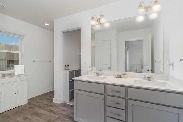 full bath with double vanity, wood finished floors, recessed lighting, and a sink