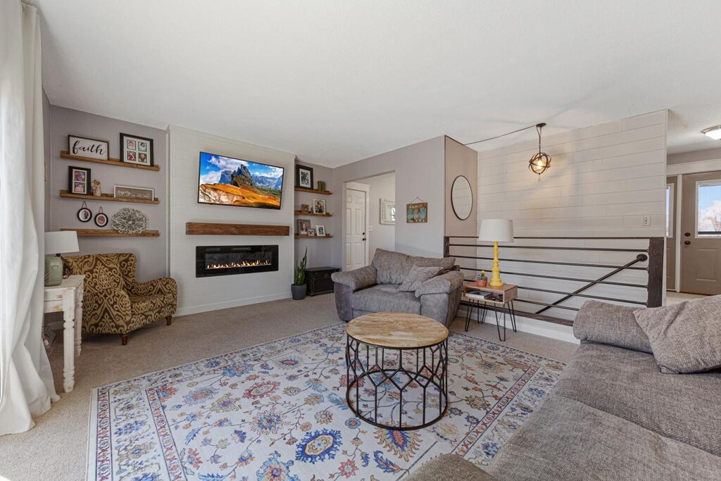 living room with a glass covered fireplace and carpet flooring