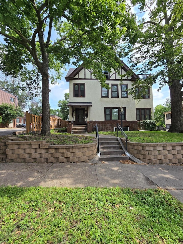 tudor home with brick siding, stucco siding, and fence