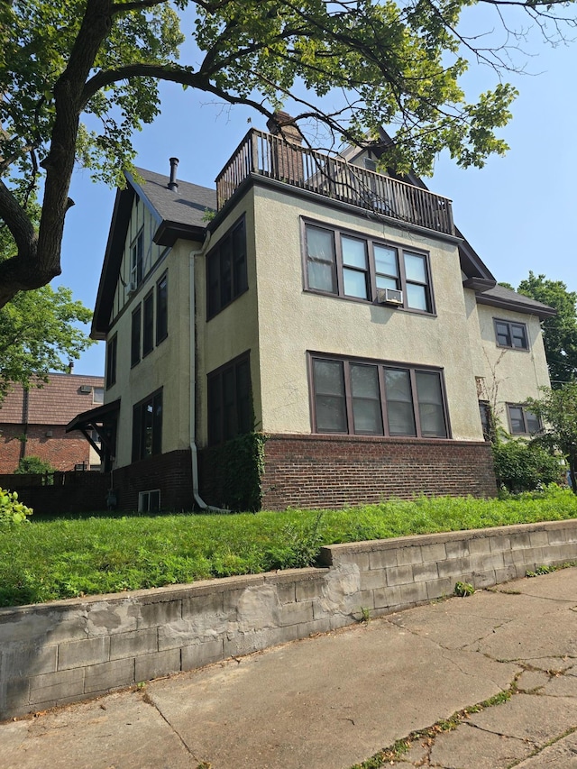 view of side of property with brick siding, a balcony, and stucco siding
