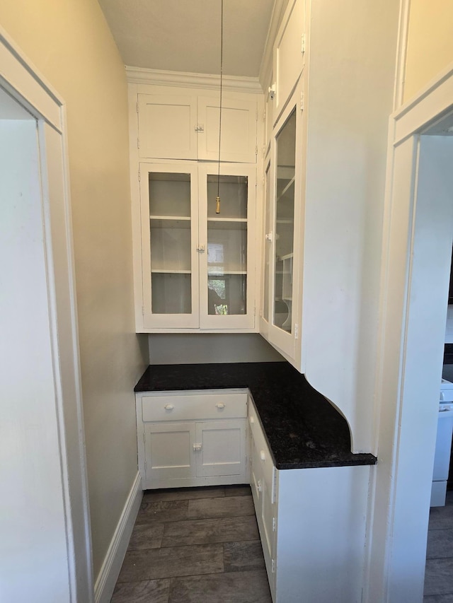 interior space featuring white cabinetry, dark wood-style flooring, baseboards, and glass insert cabinets