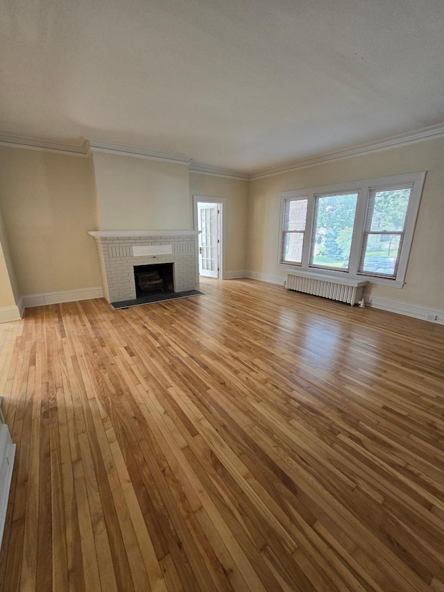 unfurnished living room with crown molding, radiator, baseboards, and hardwood / wood-style flooring