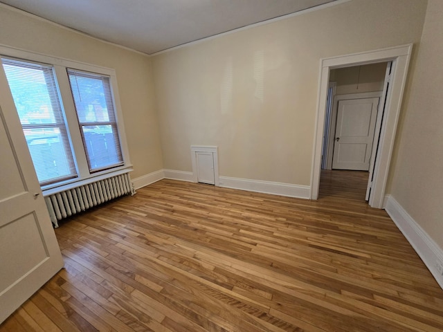 empty room with light wood-style flooring, radiator, and baseboards