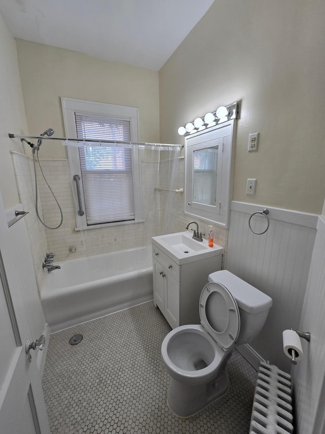 bathroom with toilet,  shower combination, radiator heating unit, a wainscoted wall, and tile patterned flooring