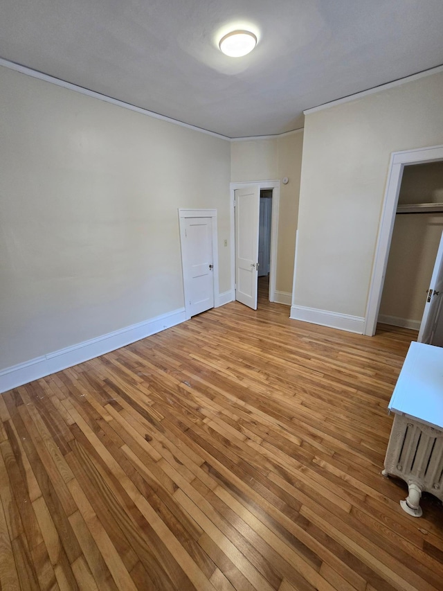 unfurnished bedroom featuring ornamental molding, baseboards, and light wood-type flooring