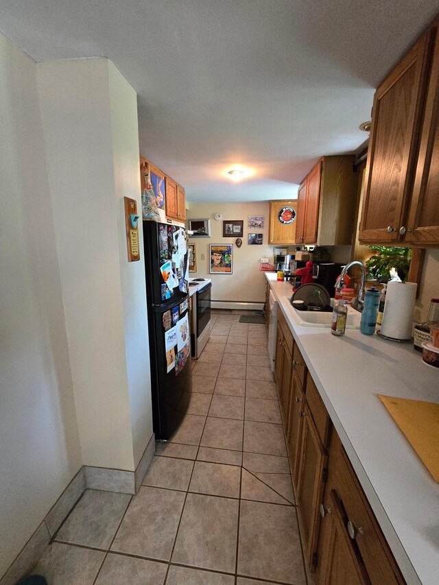 kitchen with light tile patterned floors, white appliances, brown cabinetry, light countertops, and a sink