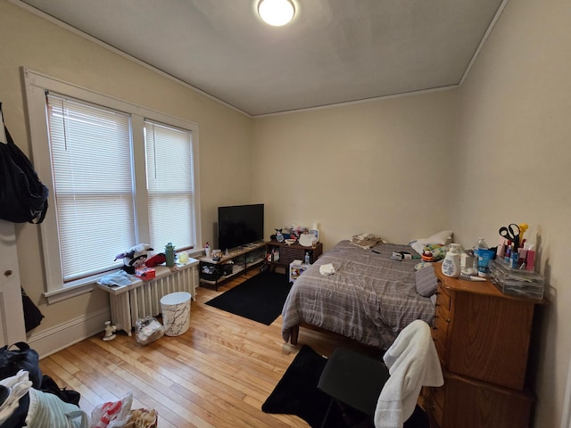 bedroom featuring hardwood / wood-style floors, crown molding, and baseboards