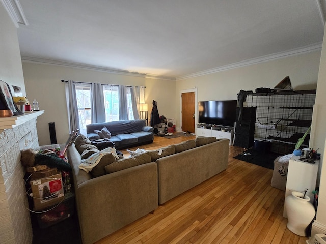 living area with a brick fireplace, light wood-type flooring, and crown molding