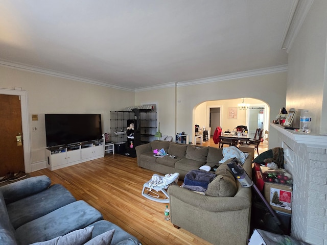 living area with arched walkways, crown molding, and wood finished floors
