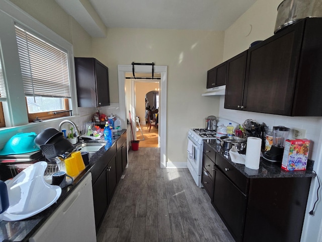 kitchen with tasteful backsplash, a sink, under cabinet range hood, white range with gas cooktop, and wood finished floors