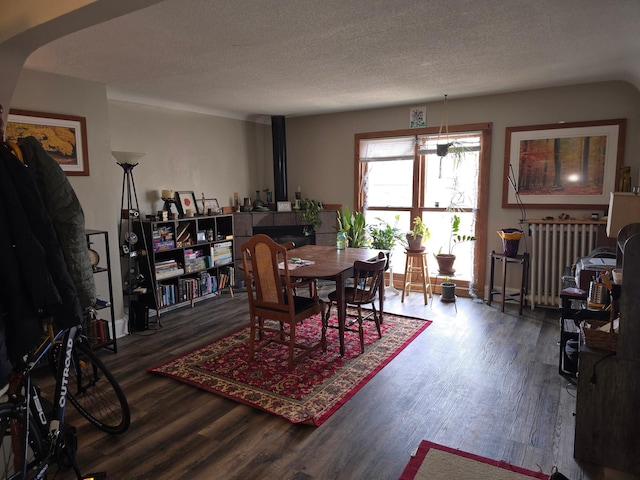 dining room with a textured ceiling, radiator, and wood finished floors