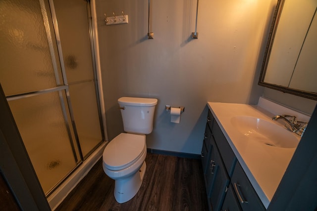 full bathroom featuring baseboards, toilet, vanity, wood finished floors, and a stall shower