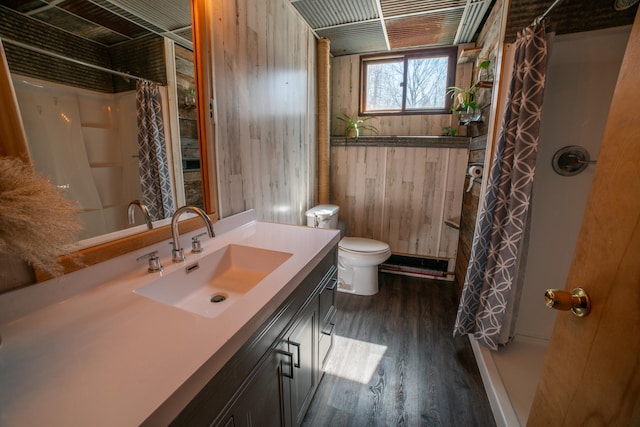 bathroom with wood walls, a shower with curtain, vanity, and wood finished floors