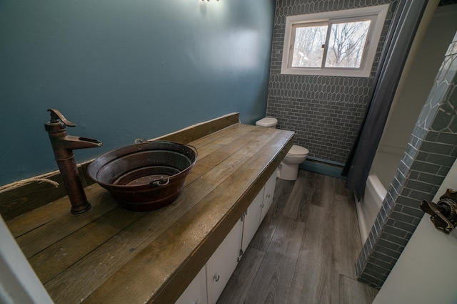 full bathroom with toilet, shower / bath combo, wood finished floors, and vanity